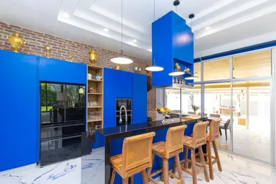 a kitchen with blue walls and a bar with chairs at Villa Valentine Phuket in Ban Thalat Choeng Thale