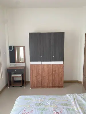 a bedroom with a large wooden cabinet and a desk at Mali Villa in Ban Suan
