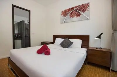 a bedroom with a large white bed with red pillows at Relaxing Holidays - 2BR Private Pool Villa Greens 8, Rawai in Rawai Beach