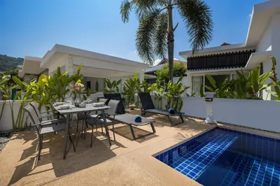 a patio with a table and chairs next to a swimming pool at Relaxing Holidays - 2BR Private Pool Villa Greens 8, Rawai in Rawai Beach
