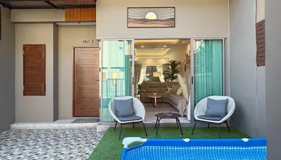 a patio with two chairs and a table and a living room at Cozy family townhouse in Chalong