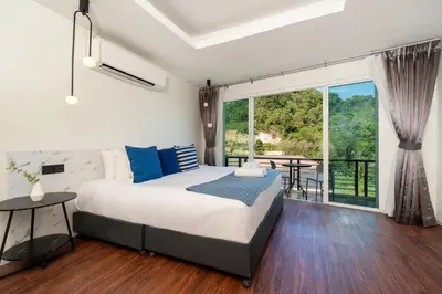 a bedroom with a bed and a balcony with a table at Patong Cliff Pool villa in Patong Beach