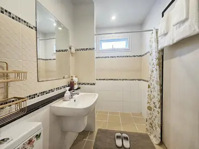 a white bathroom with a sink and a mirror at Sirihouse at Supalai Bella Thalang Phuket in Phuket