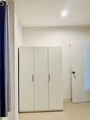 a room with two white cabinets and a wall at Sirihouse at Supalai Bella Thalang Phuket in Phuket
