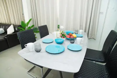 a white table with blue plates and fruit on it at Songbird Suites - Deluxe 2 Bedroom, 2 Bathroom Apt in Ban Khlong Haeng