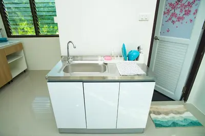 a white kitchen with a sink and a window at Songbird Suites - Deluxe 2 Bedroom, 2 Bathroom Apt in Ban Khlong Haeng