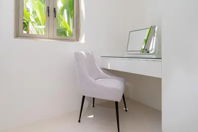 a white chair sitting next to a desk with a mirror at Coco Villas Phuket - Private Pool Villas by Escape Villas in Thalang