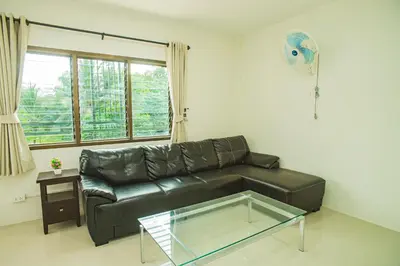 a living room with a black leather couch and a glass table at Songbird Suites - Deluxe King Suite and Scooter in Ao Nang Beach