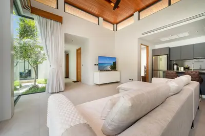 a living room with a white couch and a television at Bang Tao Botanica Modern Loft 3 bd in Ban Pak Lak