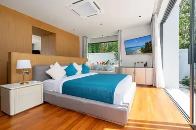 a bedroom with a large bed with a blue blanket at Bang Tao Botanica Modern Loft 4 bd S in Phuket