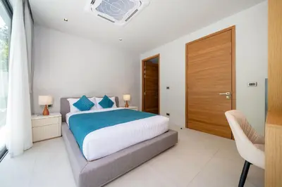 a bedroom with a large bed and a wooden door at Bang Tao Botanica Modern Loft 4 bd S in Phuket
