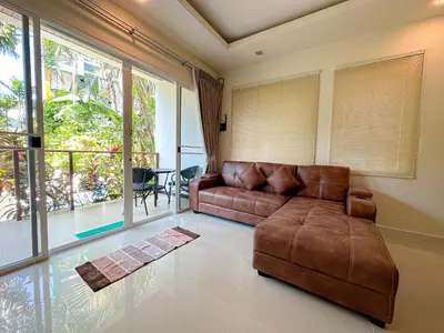 a living room with a brown couch and a large window at Oasis 1 Bedroom Apartment In Rawai in Phuket Town