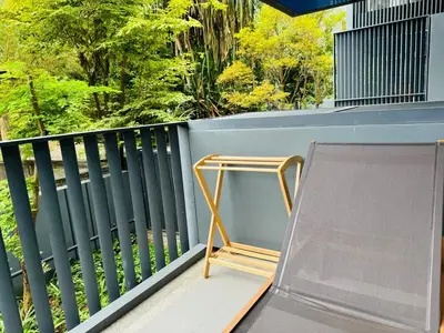 a chair on a balcony with trees in the background at Patong rooftop Pool luxury Condo with Bathtub and sofa bed big balcony in Patong Beach
