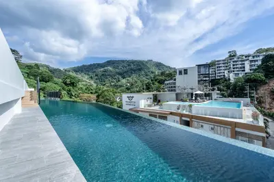 an infinity pool at a hotel with mountains in the background at Palmetto Park Residence in Karon Beach