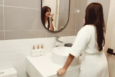 a woman brushing her teeth in front of a bathroom sink at Palmetto Park Residence in Karon Beach