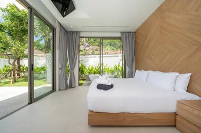 a bedroom with a white bed and large windows at Himmapana Villas - Grand Valley in Kamala Beach