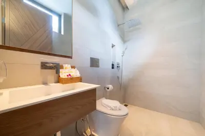 a bathroom with a toilet and a sink and a mirror at Himmapana Villas - Grand Valley in Kamala Beach