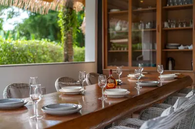 a long wooden table with glasses and a bottle of wine at kamala 1000 sqm new luxury 4 bedroom holiday pool villa extra large space amazing sunset in Kamala Beach