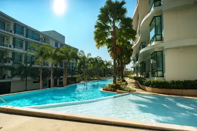a swimming pool in front of a building with palm trees at Lovely studio 5 stars Hotel La Vita in Phuket Town