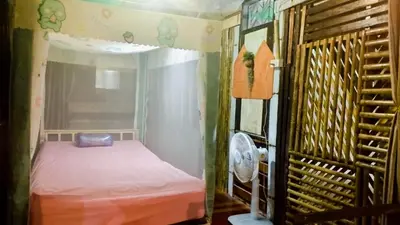 a small room with a bed and a fan at Nu Bamboo Backpacker in Phuket