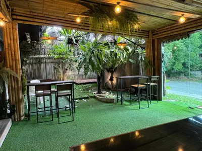 a patio with chairs and a table and a tree at Baibon3 Homestay Thalang Phuket in Ban Na Nai