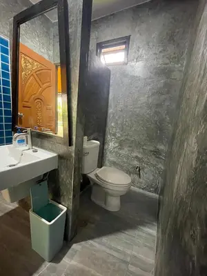 a bathroom with a toilet and a sink and a mirror at Baibon3 Homestay Thalang Phuket in Ban Na Nai