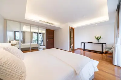 a white bedroom with a large bed and a living room at Angsana Laguna Phuket 2- bedroom, with pool access in Layan Beach