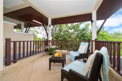 a patio with two chairs and a table on a deck at Angsana Laguna Phuket 2- bedroom, with pool access in Layan Beach