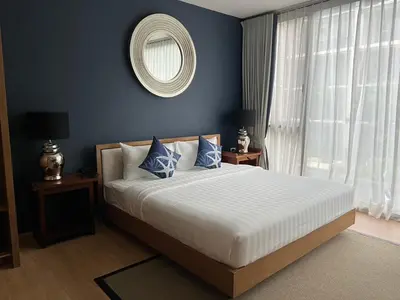 a bedroom with a large bed with blue walls and a mirror at Baan Mai Khao Condo Phuket for rent in Phuket