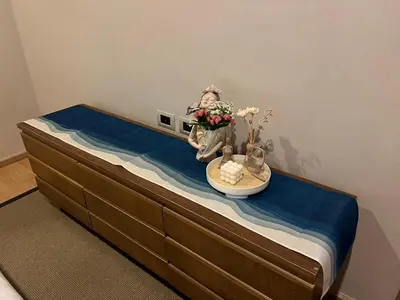 a bed with a table with a bowl of flowers on it at Baan Mai Khao Condo Phuket for rent in Phuket