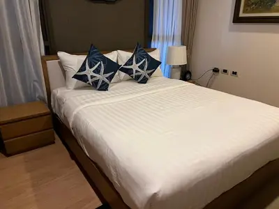 a bedroom with a large bed with blue and white pillows at Baan Mai Khao Condo Phuket for rent in Phuket
