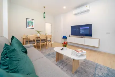 a living room with a couch and a tv and a table at Winks Beach Patong Phuket in Patong Beach