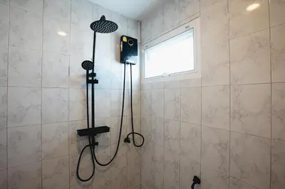 a shower in a bathroom with a shower head at Winks Beach Patong Phuket in Patong Beach