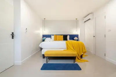 a bedroom with a bed with a yellow blanket on it at Winks House Patong Phuket 4B in Patong Beach