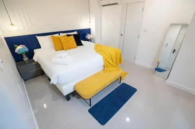 a bedroom with a white bed and a yellow chair at Winks House Patong Phuket 4B in Patong Beach