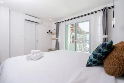 a bedroom with a white bed with a window at Winks House Patong Phuket 4B in Patong Beach