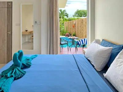 a bedroom with a blue bed and a table at At the Beach New 6-9 person Pool Villa Ao Yon Phuket in Ko Thanan