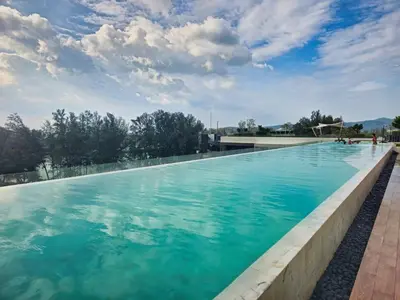 a large swimming pool with blue water at 1BDR Laguna 10 min to the Sea Roof Pool in Laguna Phuket