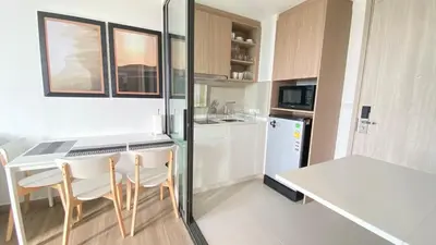 a kitchen with a table and chairs and a refrigerator at 1BDR Laguna 10 min to the Sea Roof Pool in Laguna Phuket