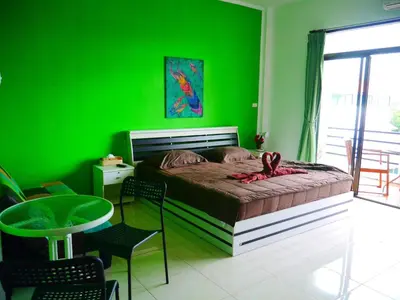 a green bedroom with a bed and a green wall at Da Puccio Rawai Guesthouse in Rawai Beach