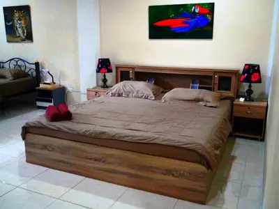 a large wooden bed in a bedroom with two lamps at Da Puccio Rawai Guesthouse in Rawai Beach