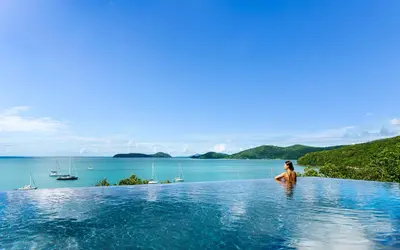 a woman standing in a infinity pool overlooking a body of water at Phuket V Building 19 Villas with Andaman Sea View Private Swimming Pool and Spa in Ban Ao Makham