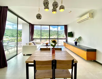 a living room with a table and a couch at 650m to beach condofast WiFi in Kamala Beach