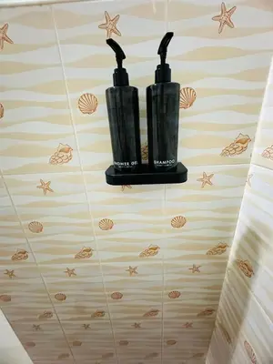 a bathroom with two black bottles on the floor at Navy Guesthouse in Ban Laem Sai
