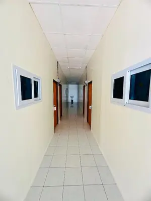 an empty hallway in an office building with two windows at Navy Guesthouse in Ban Laem Sai
