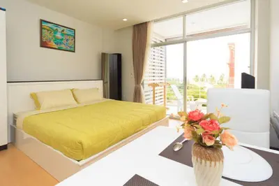 a bedroom with a yellow bed and a table with flowers at At Sea Condotel in Klong Muang Beach