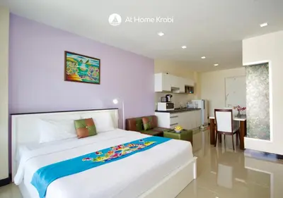 a bedroom with a large white bed and a kitchen at At Sea Condotel in Klong Muang Beach