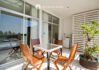 a patio with a glass table and chairs on a balcony at At Sea Condotel in Klong Muang Beach