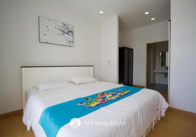 a bedroom with a bed with a blanket on it at At Sea Condotel in Klong Muang Beach