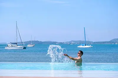 a man is playing in the water on the beach at Veranda Resort Phuket, Autograph Collection in Panwa Beach